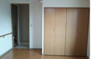 居室内部。木製の押し入れと出入口が見える。